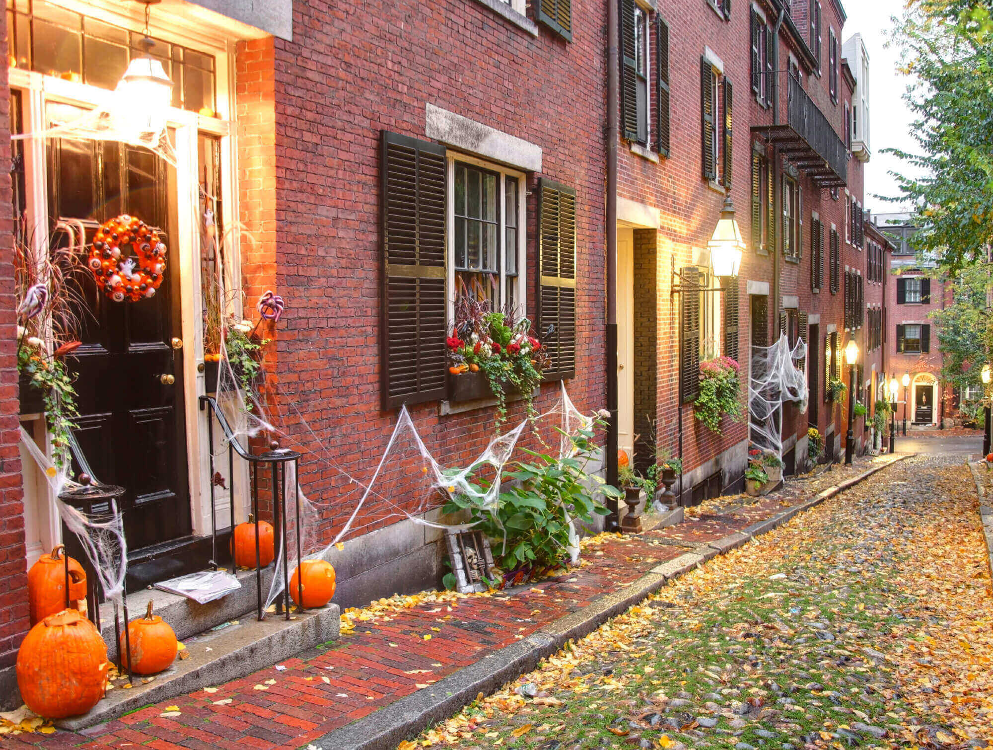 Narrow street on Acort Street, Beacon Hill, Boston offset with residences decorated for Halloween