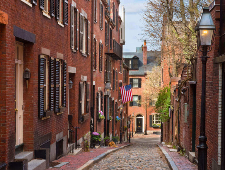 Looking downhill down narrow cobblestone acornt street in a residential neighborhood in Beacon Hill, Boston