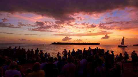Large gathering of people on the pier in Mallory Square watching the sun set in Key West, FL