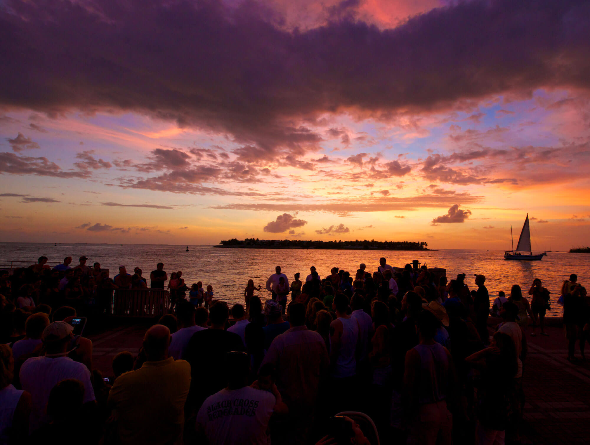 Large gathering of people on the pier in Mallory Square watching the sun set in Key West, FL