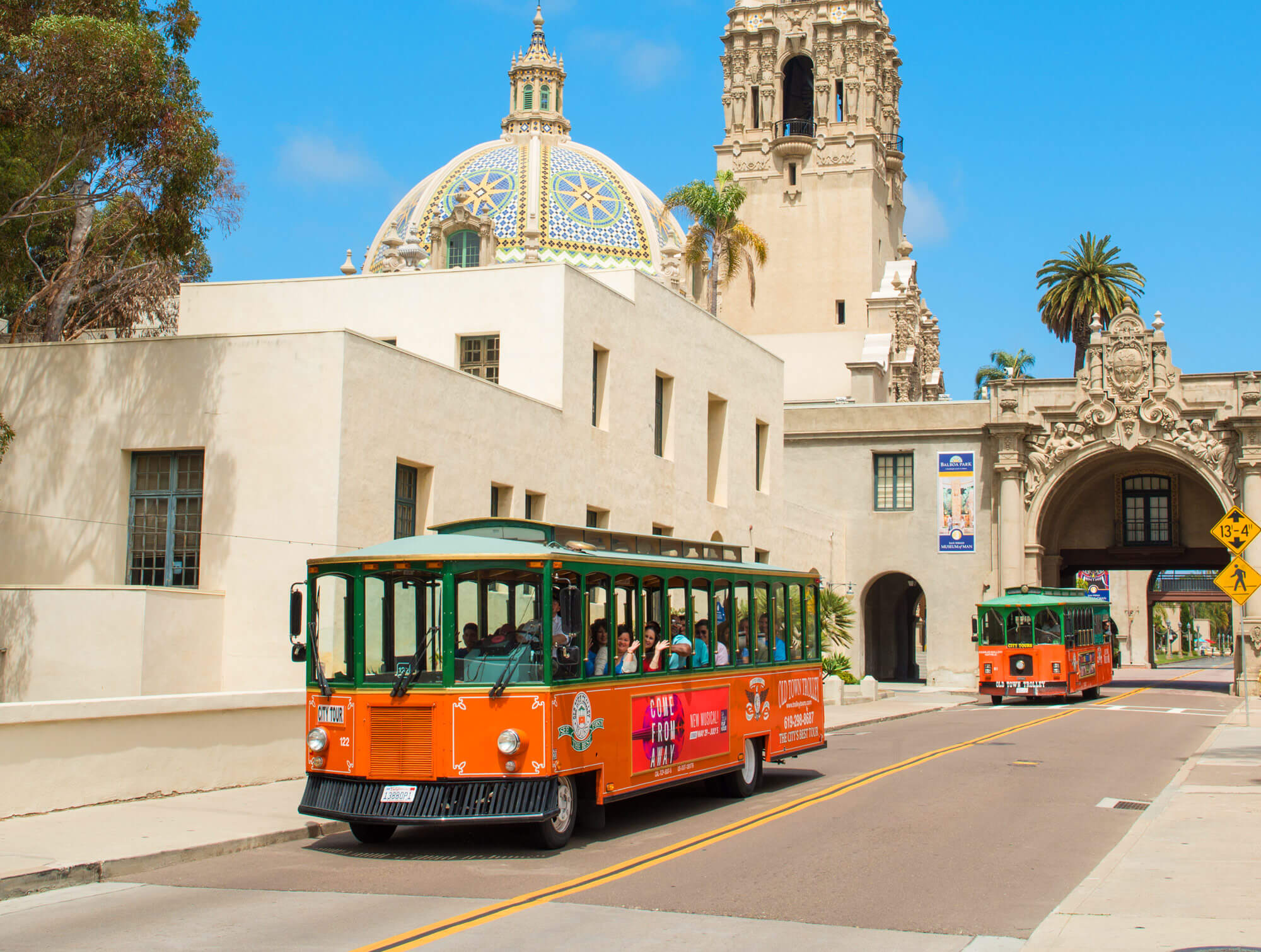 Two Old Town Trolleys driving past the rotunda of Baboa Park's Museum of Man in San Diego, CA