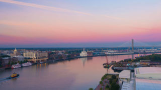 Ultimate Guide To River Street Savannah - A view of the Savannah River at dusk with the Talmadge Memorial Bridge in the background