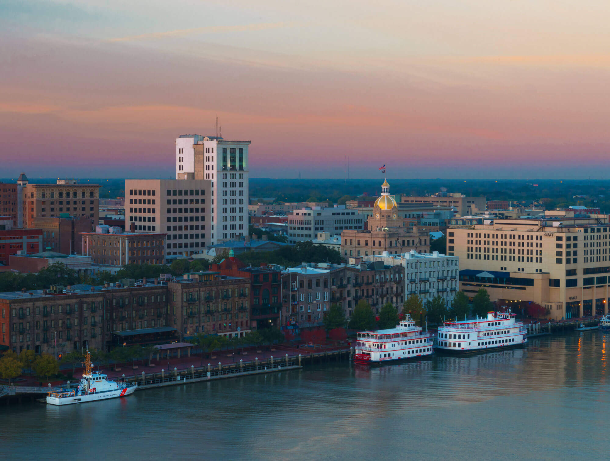 A view of downtown Savannah, GA from the Savannah River where two riverboats and a Coast Guard cutter are harbored