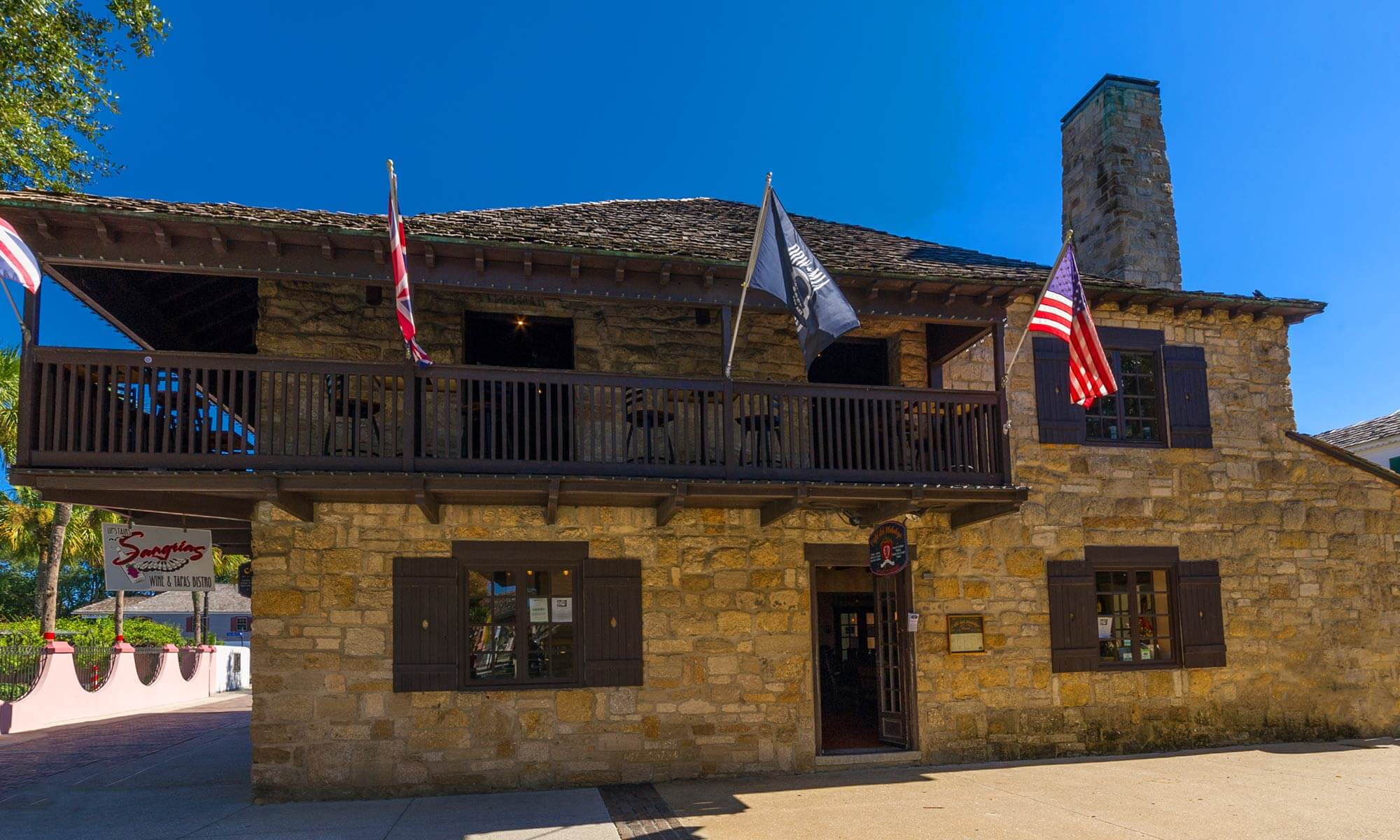 The exterior of Sangrias Wine & Tapas Bar, an odd building made of stone with a large balcony in St. Augustine, FL