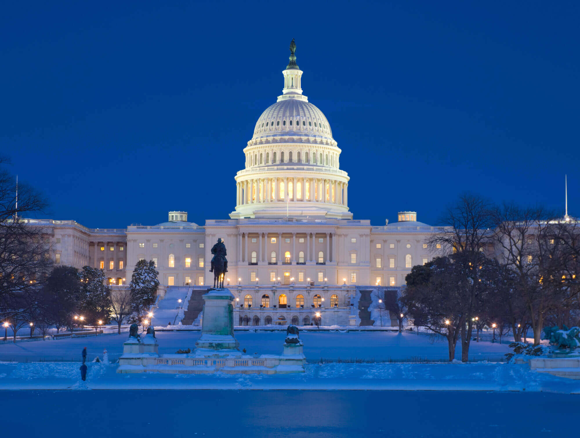 Straight ahead view of the Capitol Building at night with snow on the ground in Washington DC