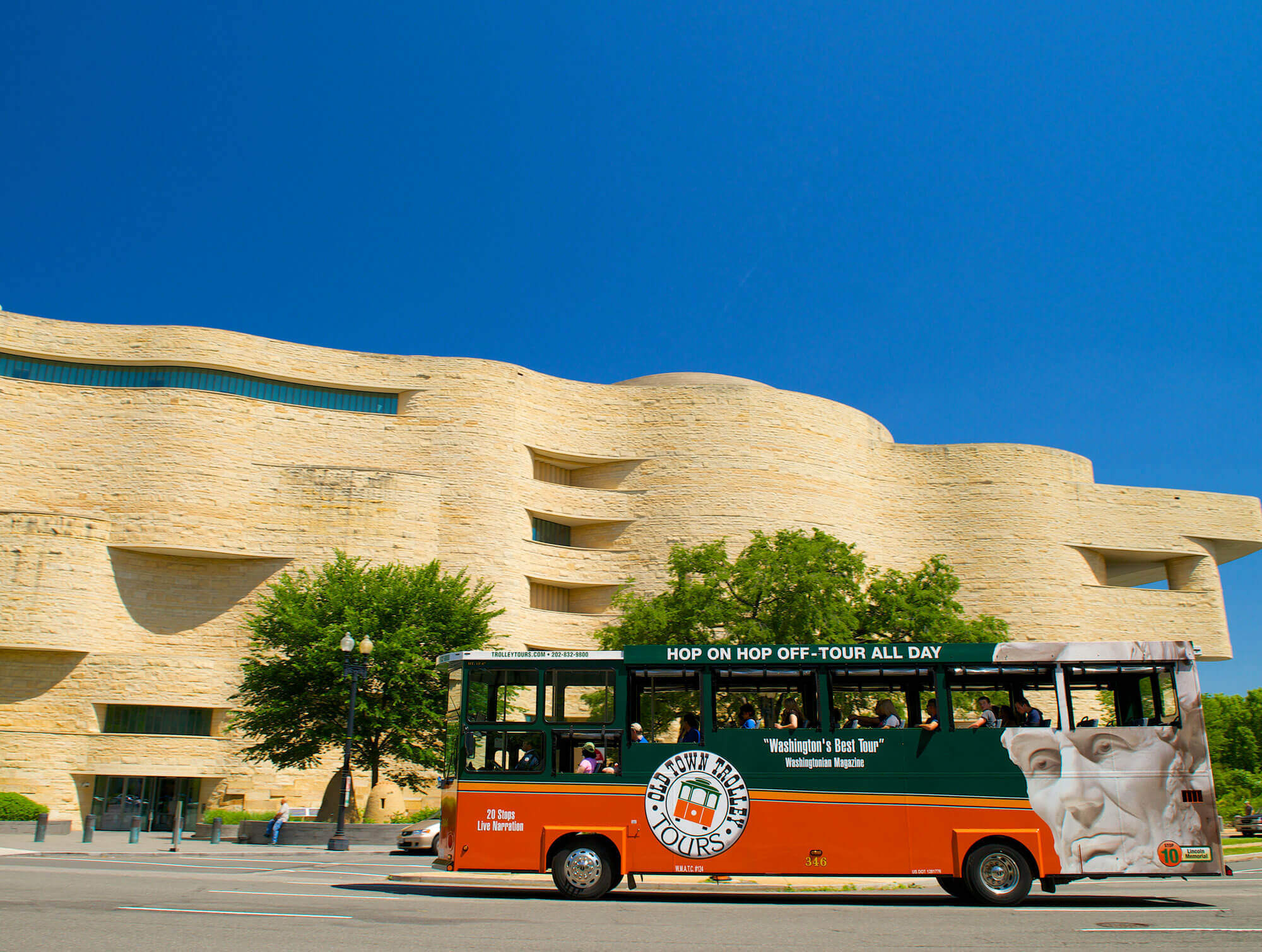 An Old Town Trolley driving past the very curvy shapes of the National Museum of the American Indian in Washington DC