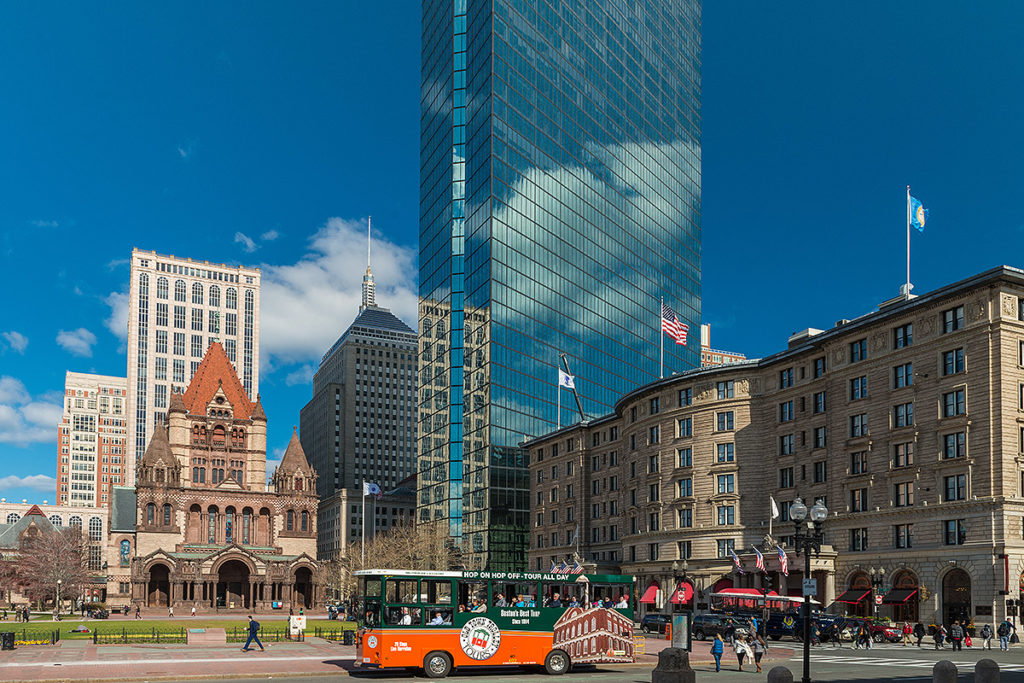 Boston Old Town Trolley driving by Trinity Church and various buildings in the background