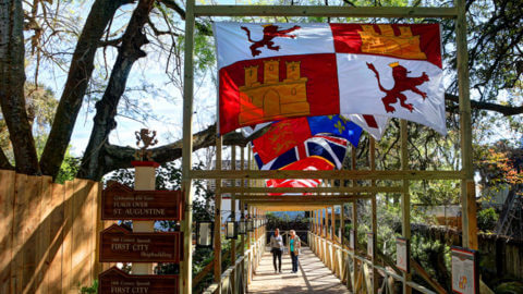 A view down a pedestrian bridge in St. Augustine's Colonial Quarter where colonial flags are hanging overhead