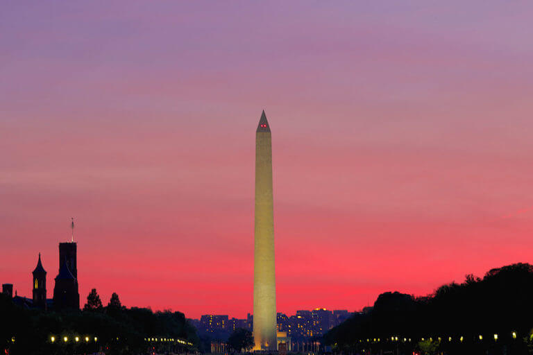 The Washington Monument set against a pink sky as night falls in Washington DC