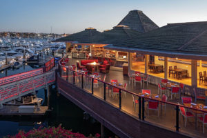 view of Hyatt Regency Mission Bay at dusk showing deck with dining tables and chairs and overlooking marina