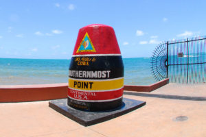 image of southernmost point landmark in front of the water, open now in key west