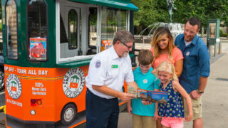 Nashville for First Timers - An Old Town trolley ticket agent standing in front of a kiosk with a map in his hand showing a family about to ride the trolley in Nashville, TN