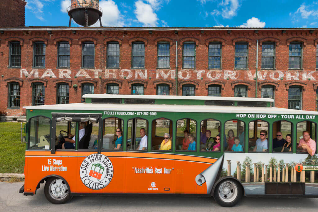 Old Town Trolley Tour passing in front of the old brick Marathon Automobile Company building