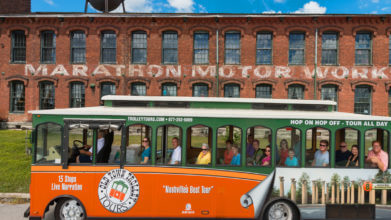 Old Town Trolley Tour passing in front of the old brick Marathon Automobile Company building