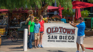 Old Town State Historic Park - Family standing next to sign that reads 'old town san diego state historic park'
