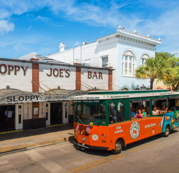 An Old Town Trolley Tour driving up Duval Street passing the famous Sloppy Joes Bar In Key West, FL