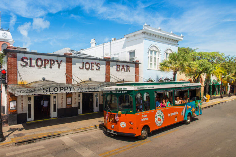 An Old Town Trolley Tour driving up Duval Street passing the famous Sloppy Joes Bar In Key West, FL