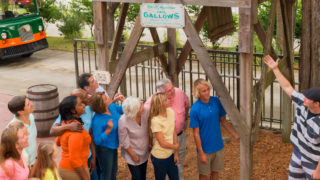 group of guests standing outside of Old Jail Museum in St. Augustine, FL while a tour guide points to the gallows