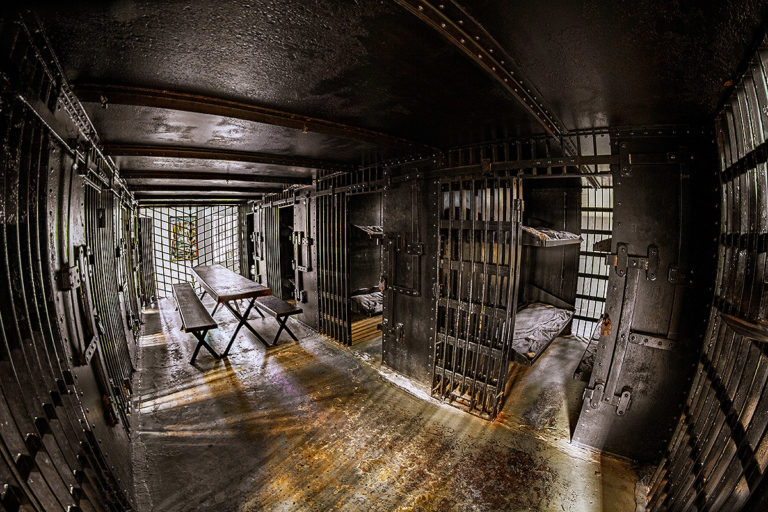 interior shot of the Old Jail featuring open cells with beds and a picnic table