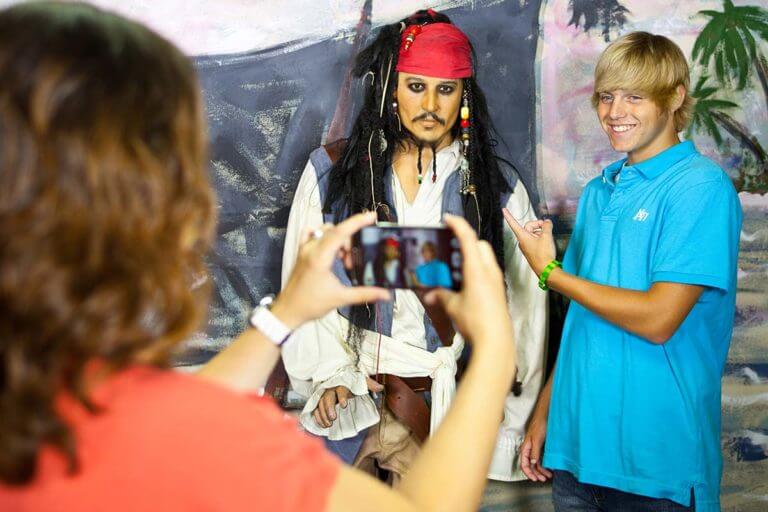 A person taking a photo of a young man standing next to a likeness of actor Johnny Depp as Captain Sparrow in Potter's Wax Museum in St. Augustine, FL