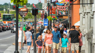 A street view of Nashville's Lower Broadway district teeming with people walking and cars