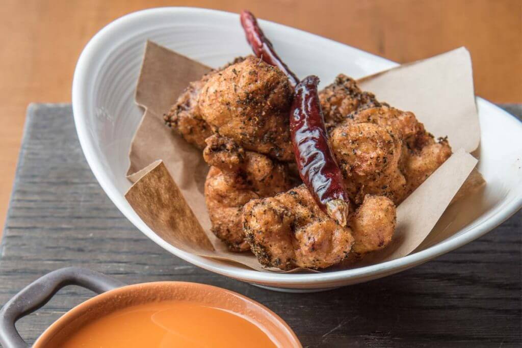 picture of a food plate showing a fried Indian inspired meal of crispy chicken and ghost pepper sauce