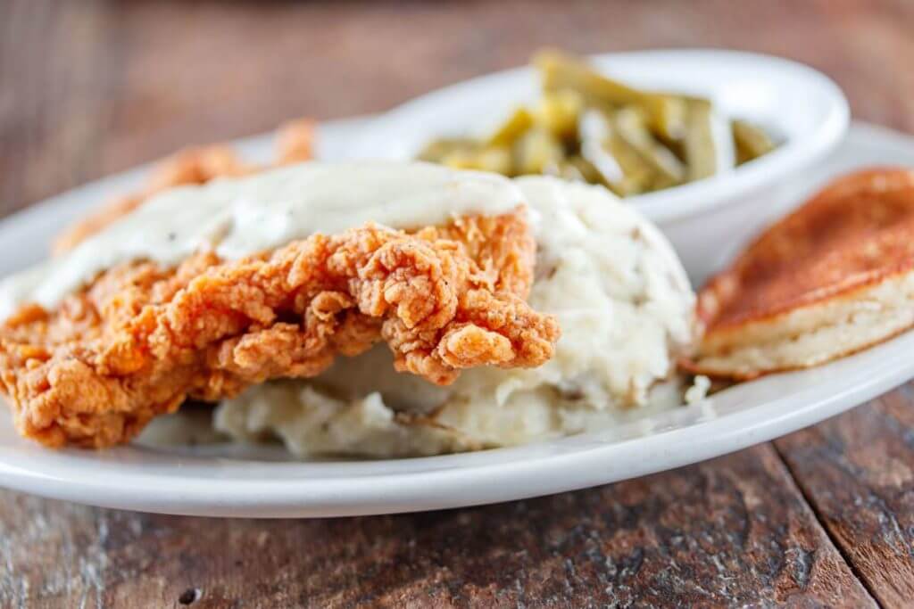 picture of a dinner plate with fried chicken, mashed potatoes and green beans