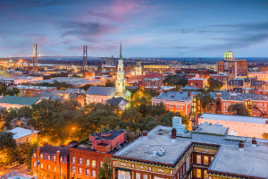 Savannah, Georgia skyline at dusk featuring rooftops in the foreground and Talmadge Bridge in the background
