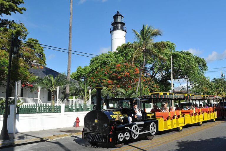 conch tour train driving past key west lighthouse