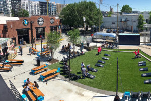 Ole Smoky Distillery featuring a lawn with corn hole games, picnic tables and facility where guests are getting drinks