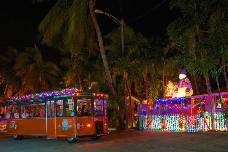 picture of key west old town trolley at night driving past a house decorated with holiday lights