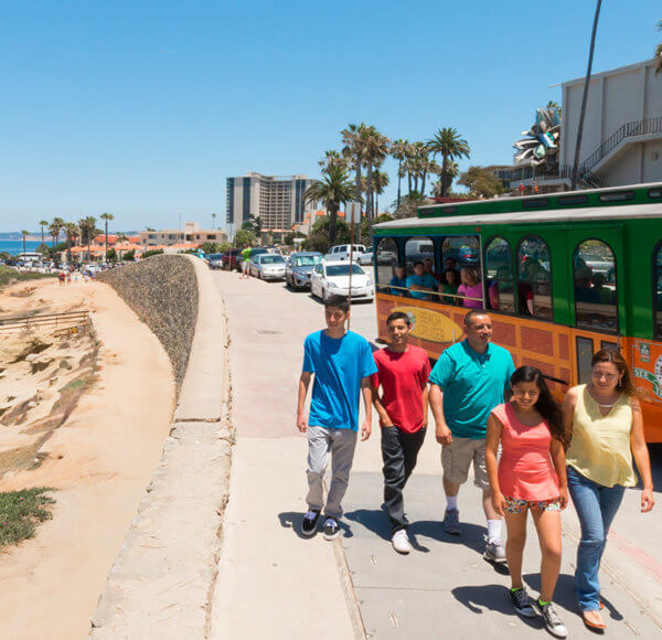 Family walking along beach with Old Town Trolley San Diego Beach Tour