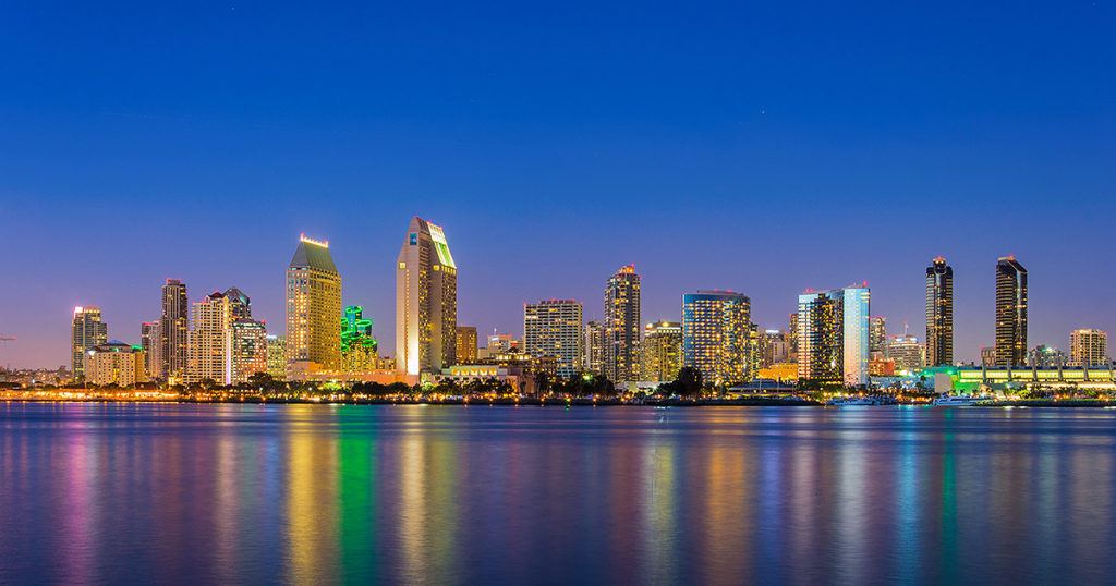 San Diego city skyline at night with building lit up and their reflections on the water