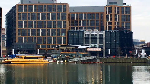 view of washington dc wharf with buildings in background and water in foreground