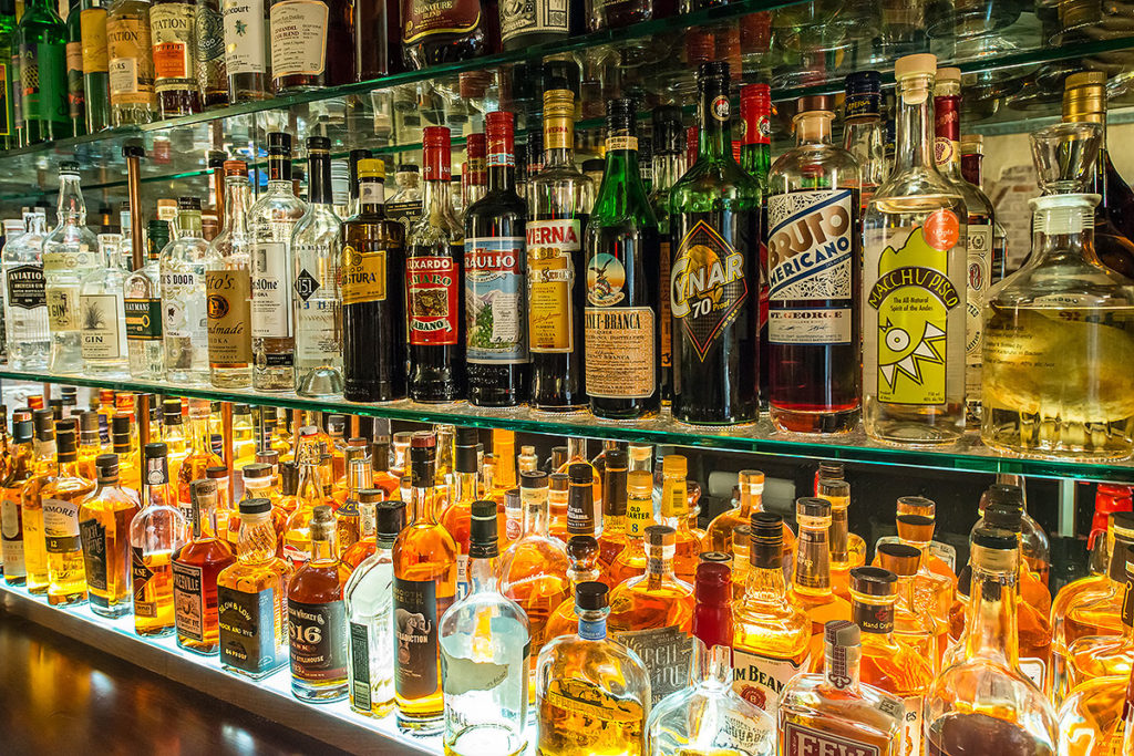 rows of liquor bottles sitting on glass shelves