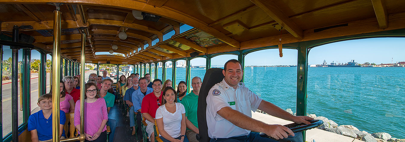 interior picture of a san diego old town trolley showing guests and conductor seated with windows showing view of the ocean