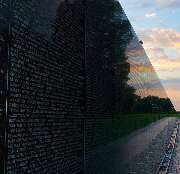 Vietnam War Memorial Wall showing names carved on the wall and the Washington Monument obelisk in the background