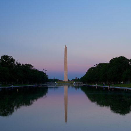 Washington monument obelisk at dusk and its reflection on Lincoln Memorial reflecting pool