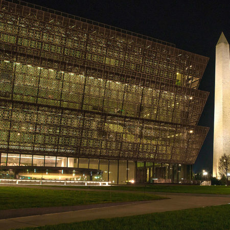 night time picture of National Museum of African American History and Culture with the Washington Monument obelisk to the right