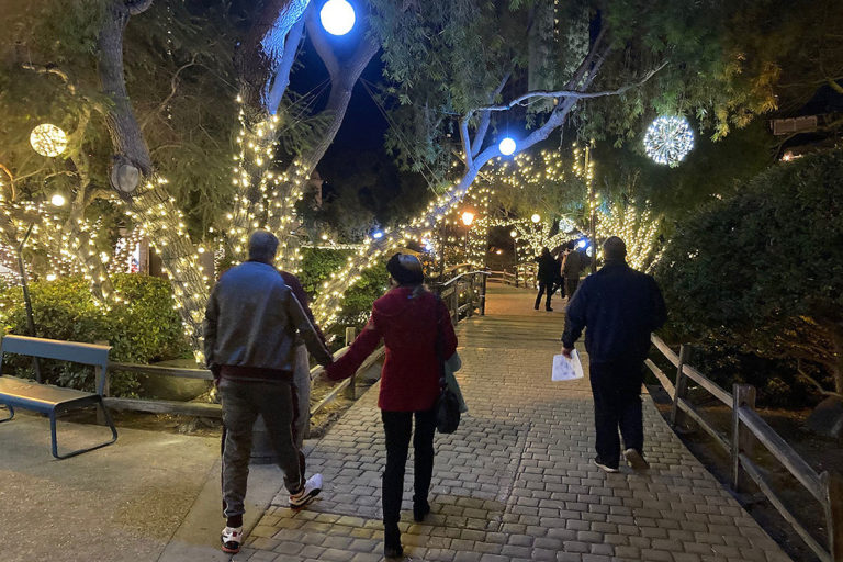 nighttime picture of guests strolling Seaport Village decorated with holiday lights