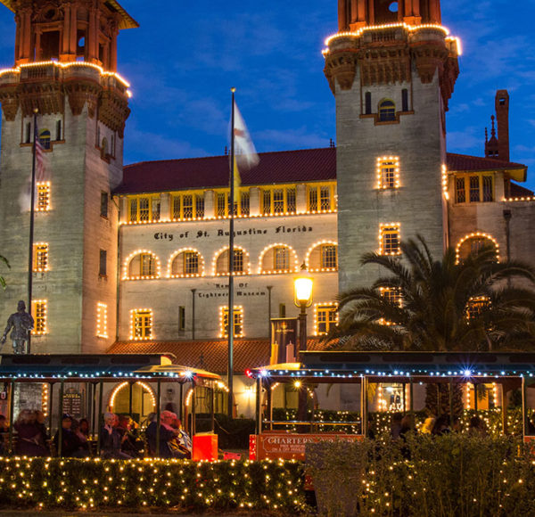 St. Augustine old town trolley nights of lights tour driving past lightner museum at night decorated with holiday lights