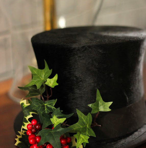 picture of a top hat with holly leaves on top of a table