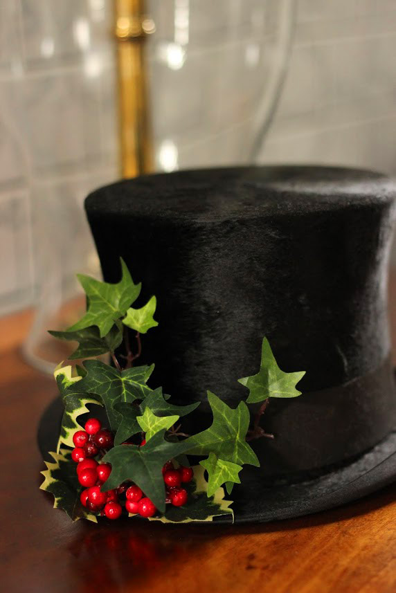 picture of a top hat with holly leaves on top of a table