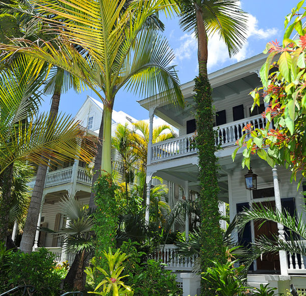 Key West two-floor houses with wrap-around porches and surrounded by foliage including palm trees