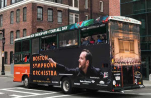 boston trolley featuring ad advertisement wrapped around trolley showing a male conductor with a baton and the words 'BOSTON SYMPHONY ORCHESTRA'