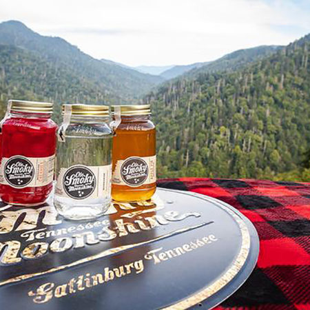 Ole Smoky Distillery moonshine bottles sitting on top of a surface with mountains in the background