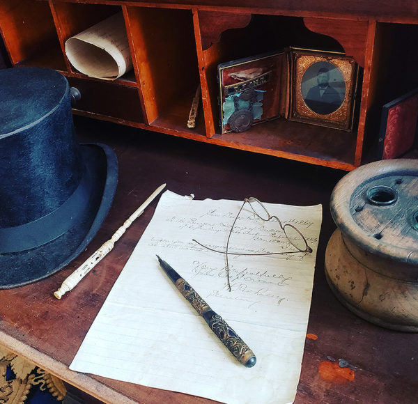 Whaley House writing desk featuring a hat, paper, quill and ink pot