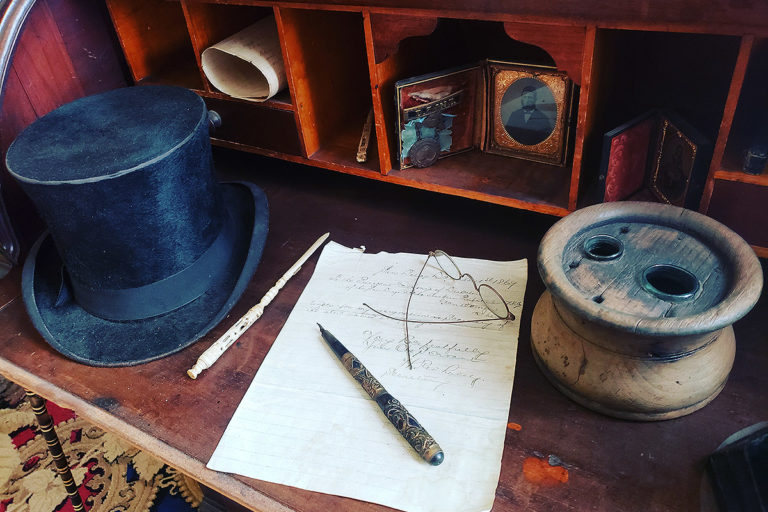Whaley House writing desk featuring a hat, paper, quill and ink pot