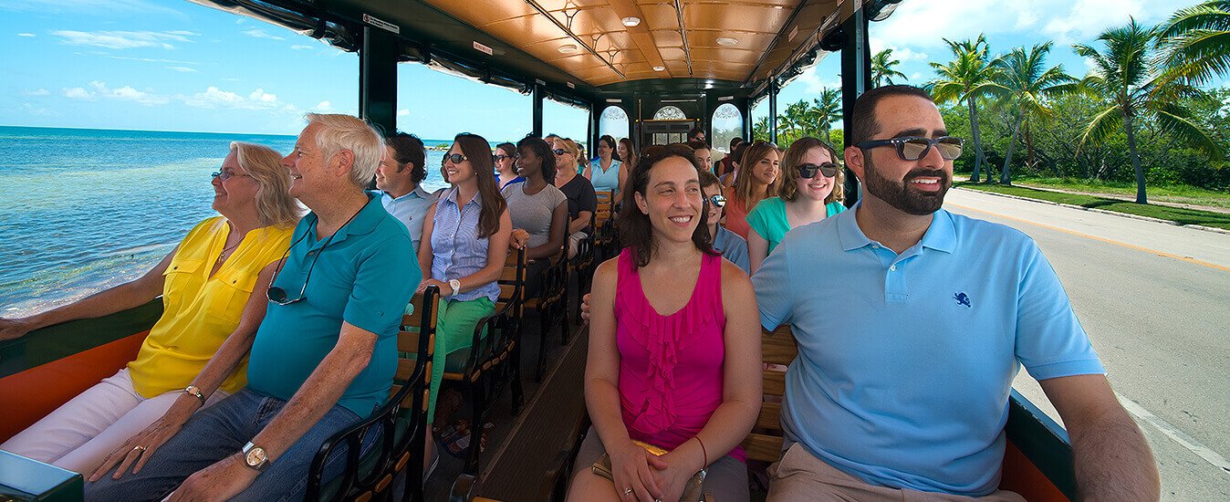 picture showing guests inside old town trolley looking out the windows showing ocean on the left and palm trees on right