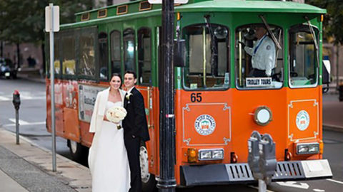 bride and groom standing in front of boston trolley